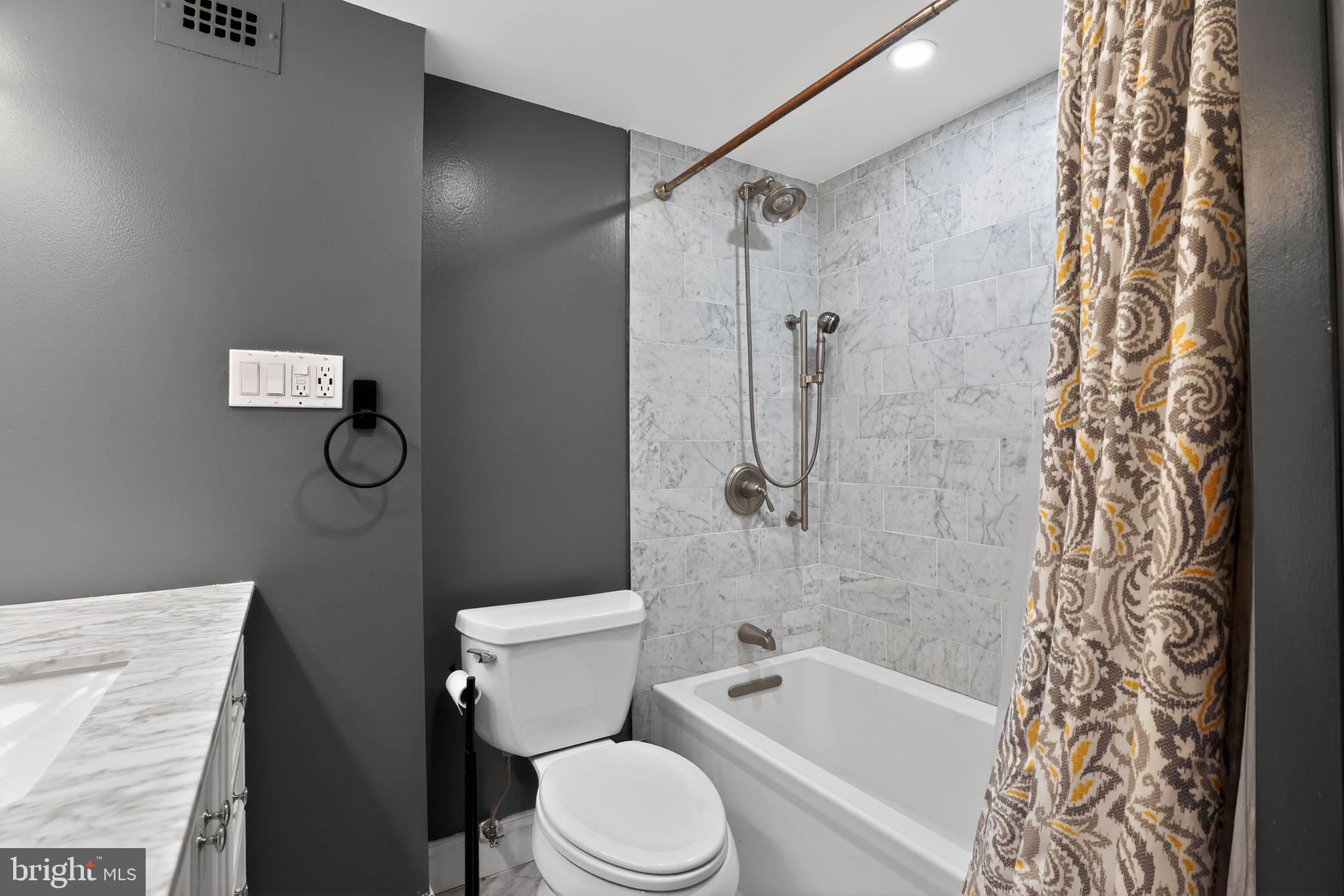 1435 4th Street Southwest, Unit B201 Washington, DC 20024 - Photo 12 of 13 a white toilet sitting next to a bath tub and shower curtain