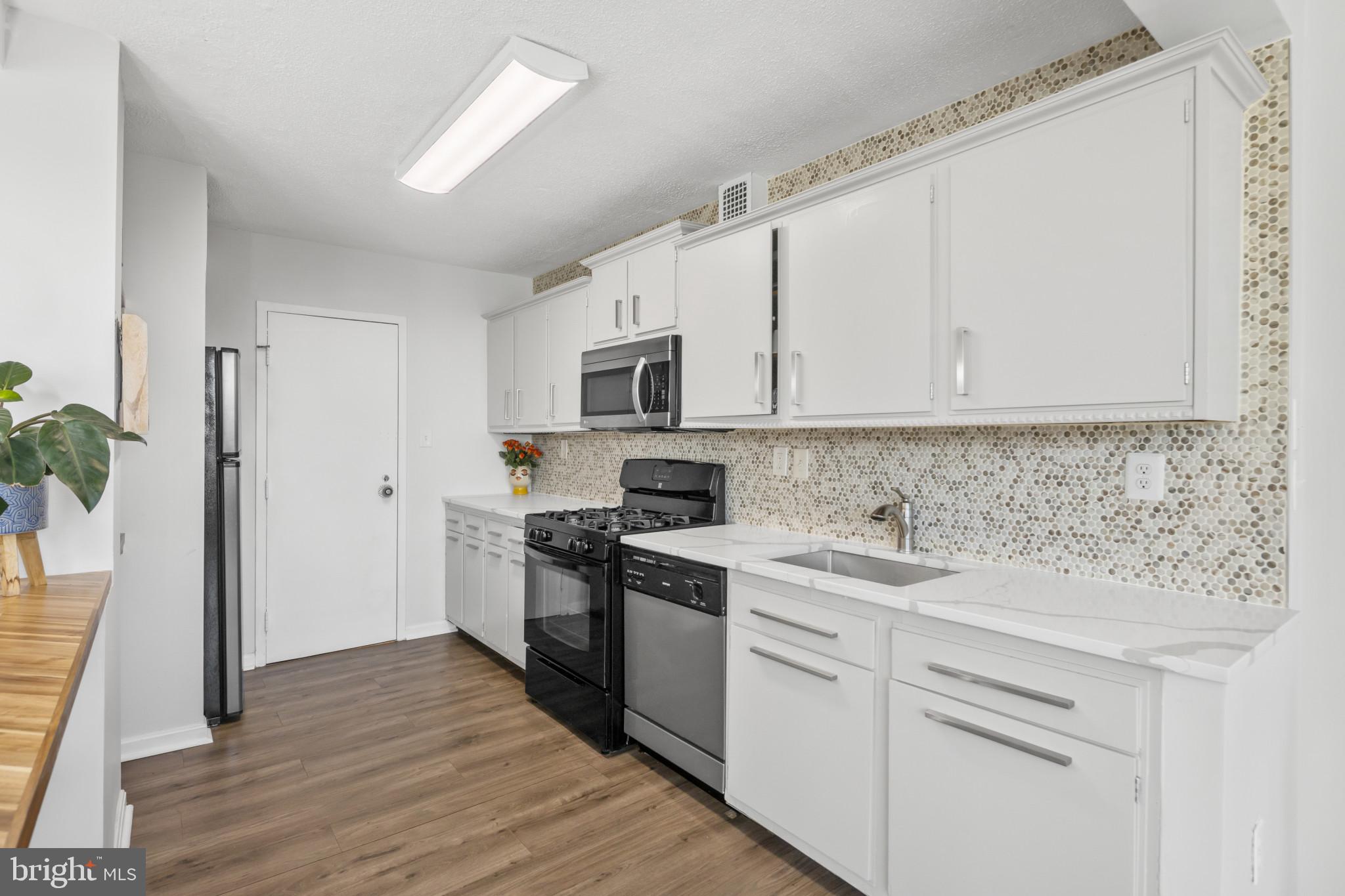 4401 Roland Avenue, Unit 310 Baltimore, MD 21210 - Photo 12 of 24 a kitchen with cabinets stainless steel appliances a sink and wooden floor
