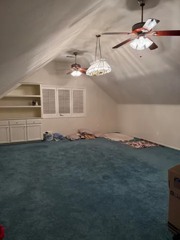 a view of a livingroom with a chandelier fan and windows