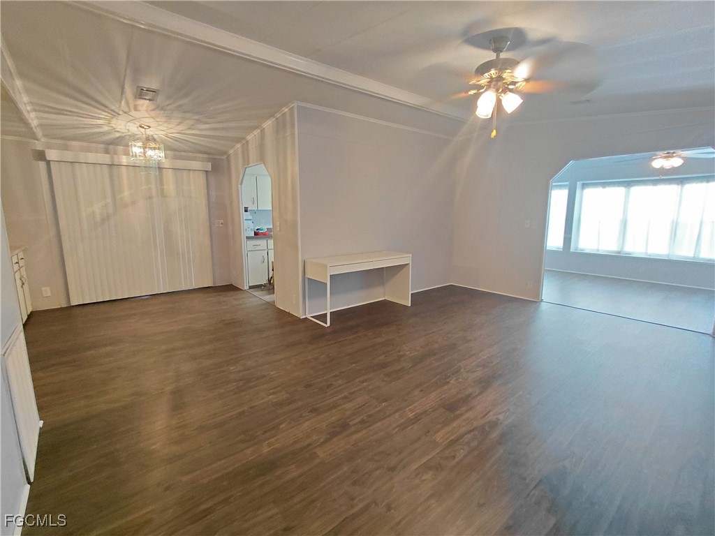 708 Bowden Road Clewiston, FL 33440 - Photo 23 of 44 an empty room with wooden floor chandelier fan and windows