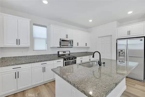 a kitchen with stainless steel appliances granite countertop a sink a stove and white cabinets