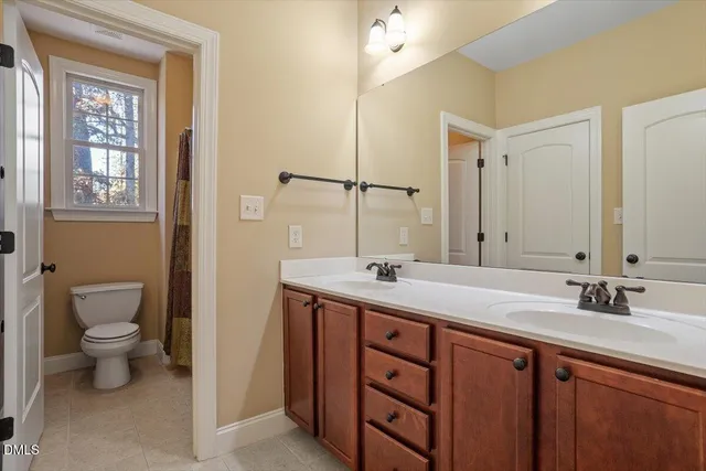 a bathroom with a toilet a sink a mirror and a window