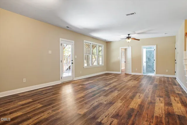 a view of an empty room with window and wooden floor
