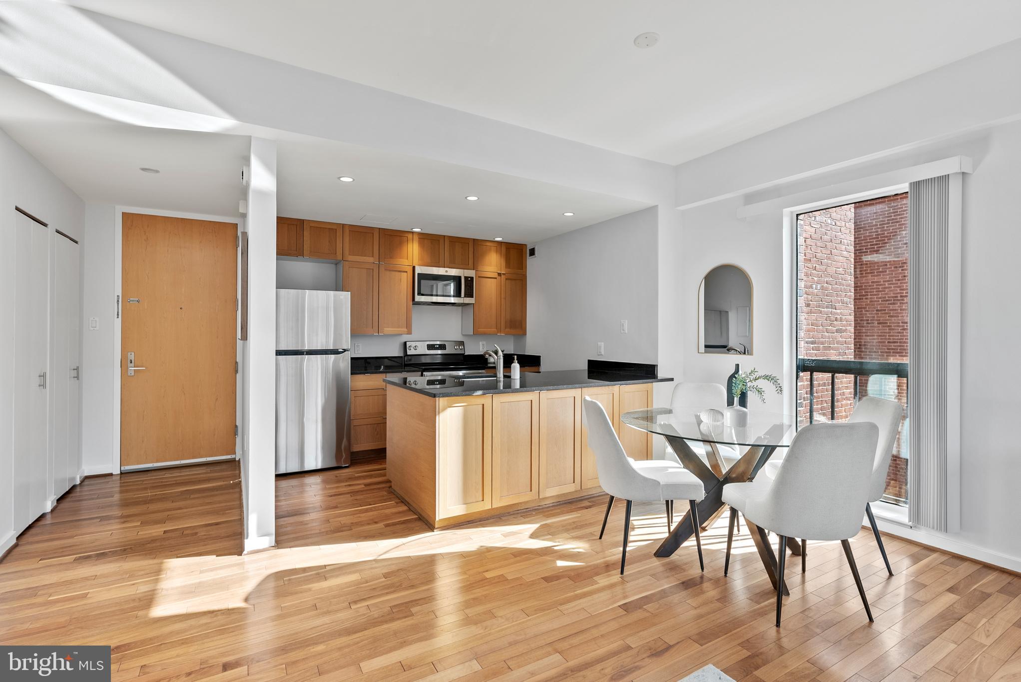 3251 Prospect Street Northwest, Unit 319 Washington, DC 20007 - Photo 6 of 16 a kitchen with stainless steel appliances kitchen island granite countertop a refrigerator a stove a dining table and chairs with wooden floor