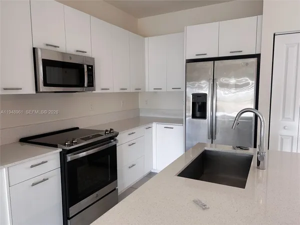 a kitchen with stainless steel appliances a stove microwave and sink