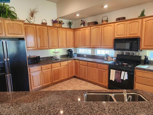 a kitchen with stainless steel appliances a sink a stove a refrigerator cabinets and a window