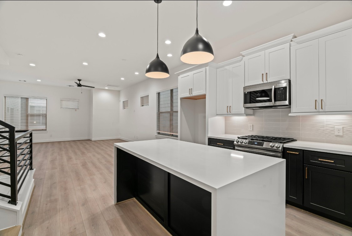 816 Curtin Street, Unit D Houston, TX 77018 - Photo 20 of 30 a kitchen with a stove kitchen island stainless steel appliances cabinets a sink and a stove