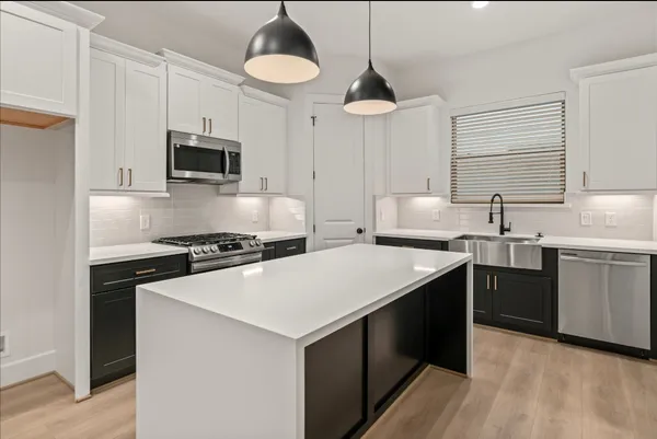 a kitchen with stainless steel appliances a sink a stove a microwave a center island and cabinets
