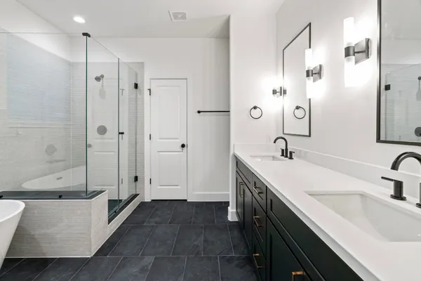 a bathroom with a double vanity sink a toilet and shower