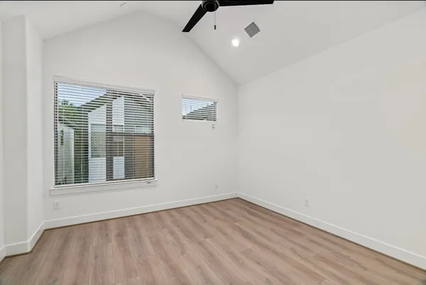an empty room with wooden floor and windows