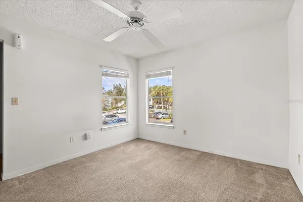 an empty room with windows and fan