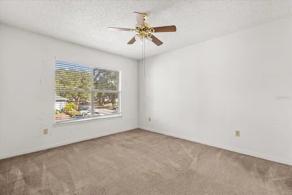 an empty room with a window and a ceiling fan