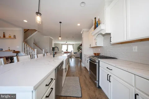 a kitchen with kitchen island a stove a chandelier a sink a counter space and cabinets