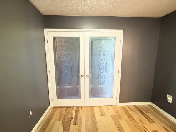 a view of an empty room with wooden floor and a bathroom