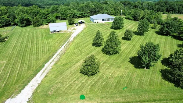 a green field with lots of trees in the background