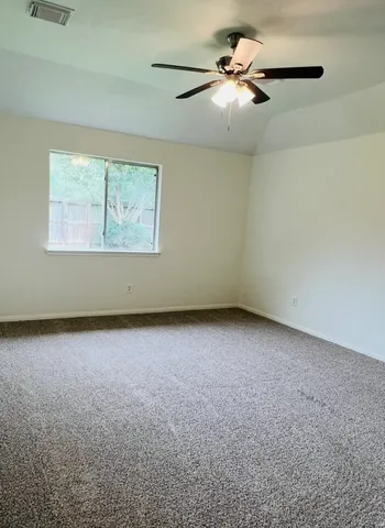 an empty room with a chandelier fan and windows
