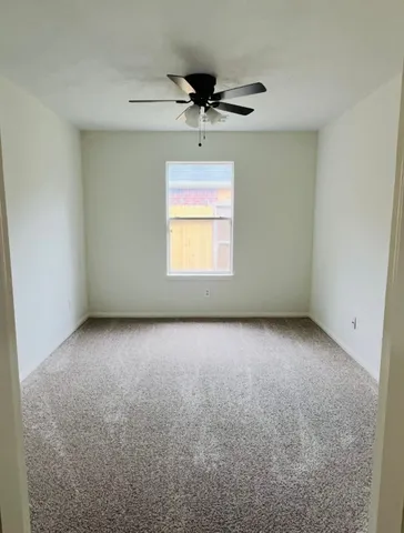 an empty room with a ceiling fan and window