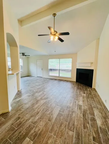 a view of empty room with wooden floor and fan