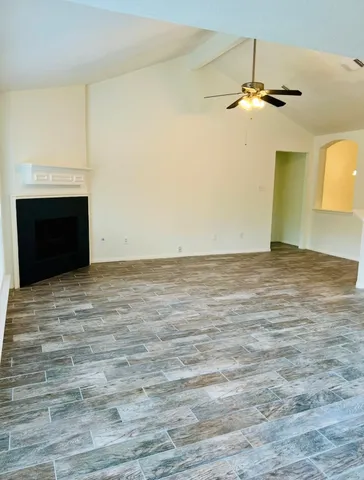 a view of an empty room with window and chandelier fan
