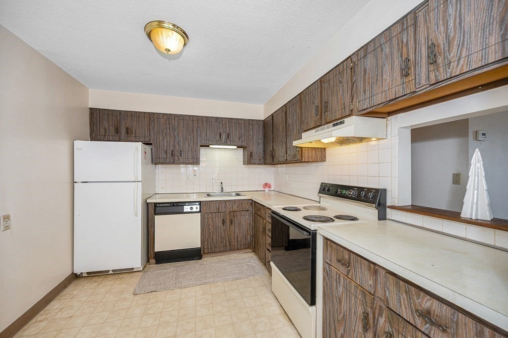 3 Summit Drive, Unit 16 Reading, MA 01867 - Photo 8 of 21 a kitchen with stainless steel appliances a stove a sink and a refrigerator