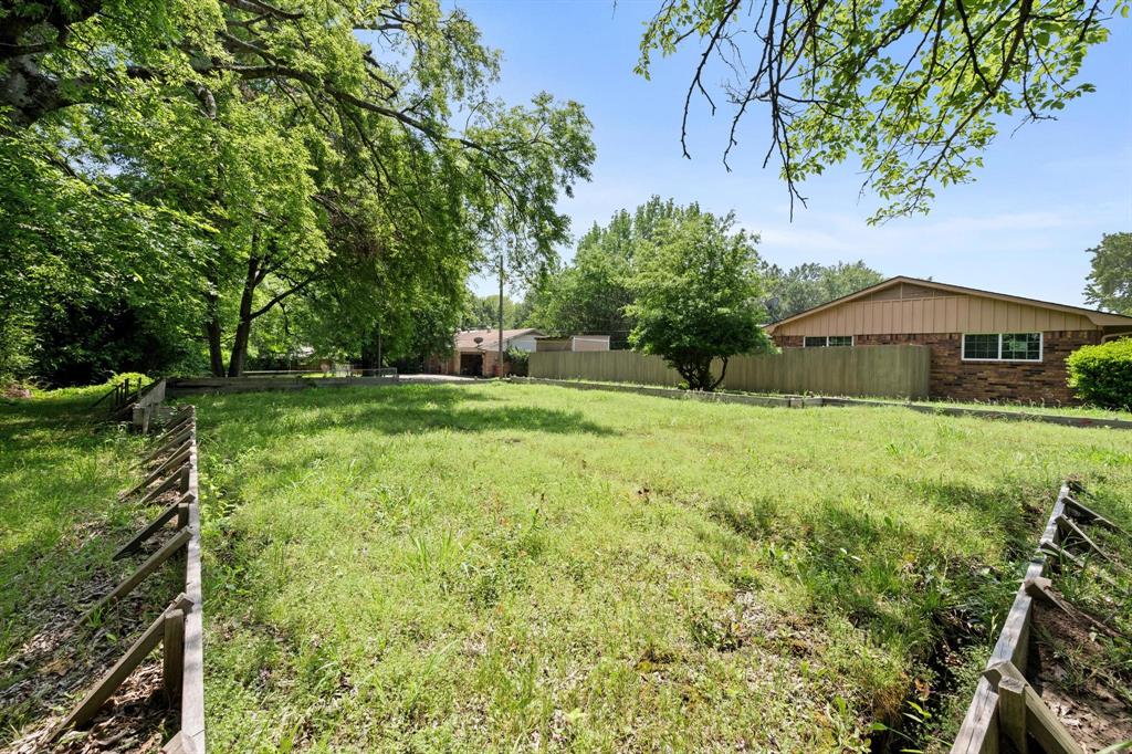 602 Wes Michael Road Bonham, TX 75418 - Photo 9 of 16 a view of a garden with a bench under an umbrella