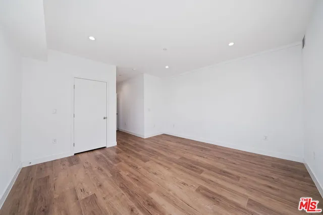 a view of an empty room with wooden floor and closet