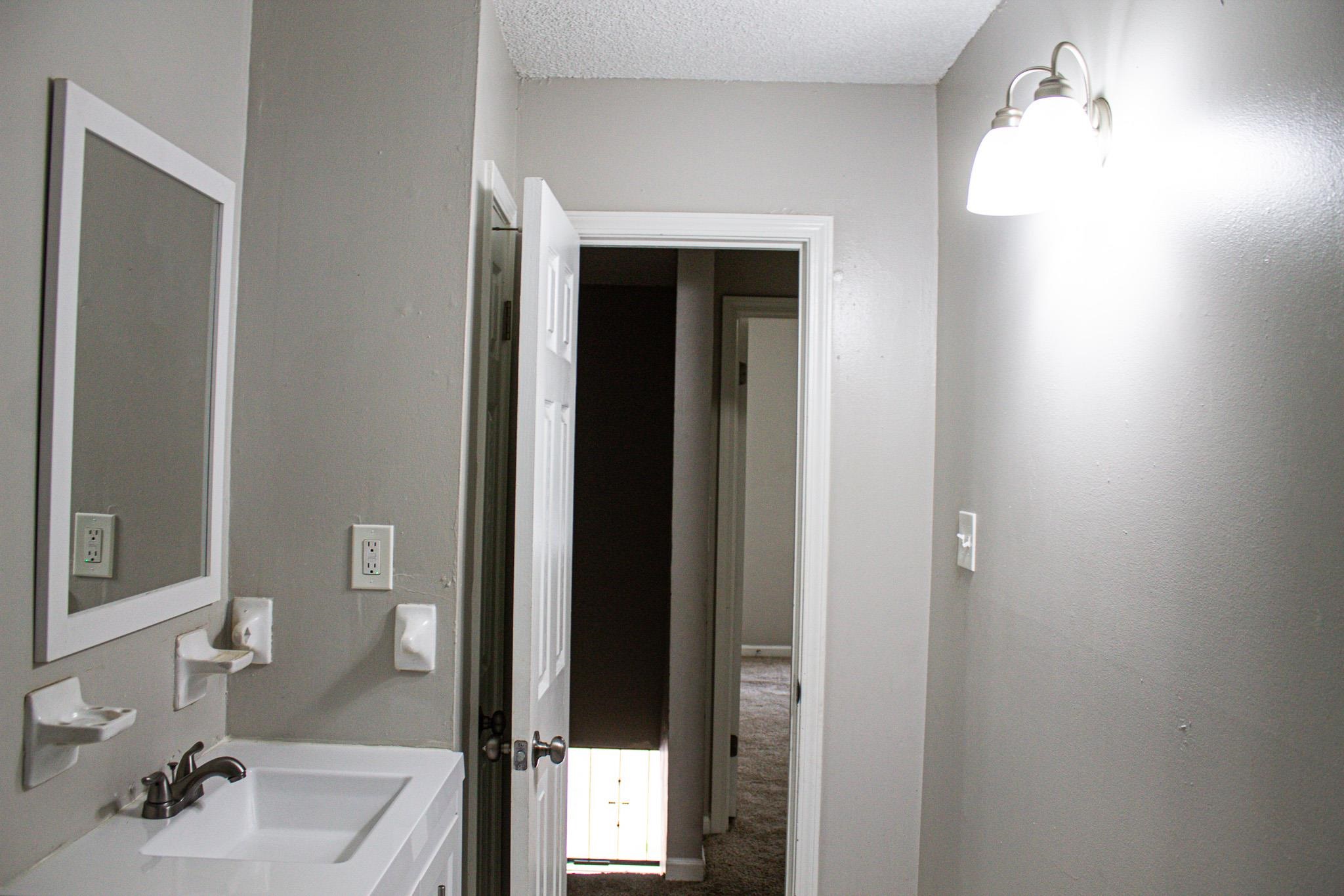 3592 Christine Road Memphis, TN 38118 - Photo 10 of 13 Bathroom vanity with a rectangular sink, wall-mounted mirror, and brushed chrome faucet