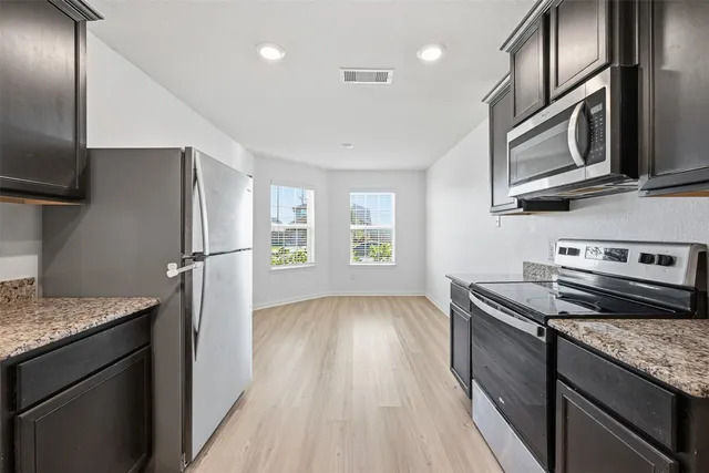 a kitchen with stainless steel appliances granite countertop wooden cabinets and a stove top oven