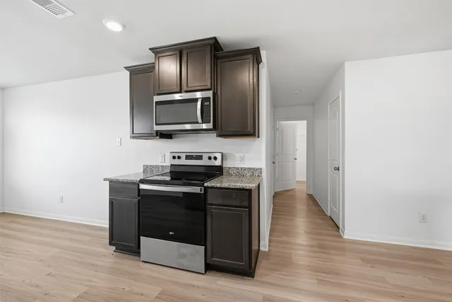 a kitchen with stainless steel appliances wooden cabinets and wooden floor
