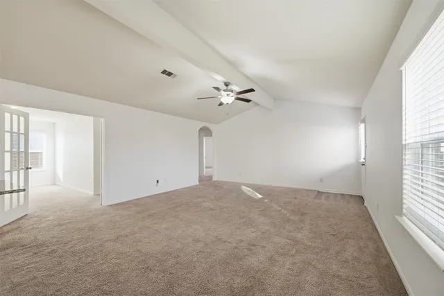 an empty room with windows and chandelier fan