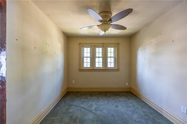 an empty room with a ceiling fan and window