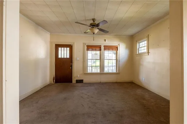 an empty room with chandelier fan and windows
