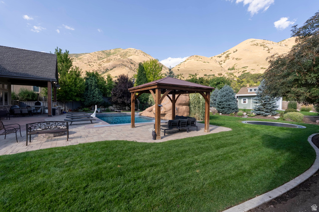 687 South 2080th Street East Springville, UT 84663 - Photo 94 of 149 Expansive backyard featuring a large swimming pool with a rock waterfall, a covered patio, a separate wood gazebo with a shingled roof, a manicured lawn, and mature landscaping