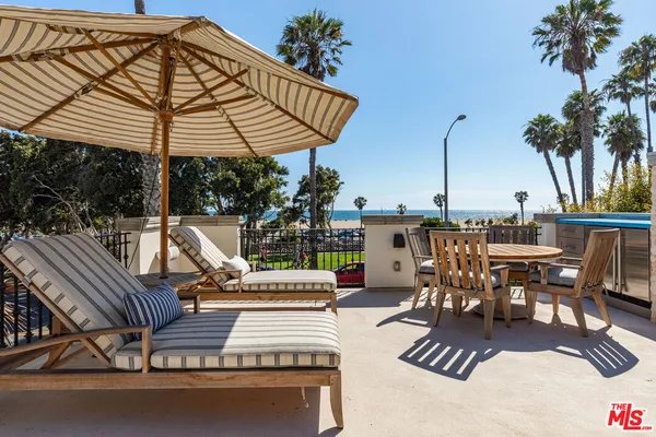a view of a patio with couches table and chairs under an umbrella