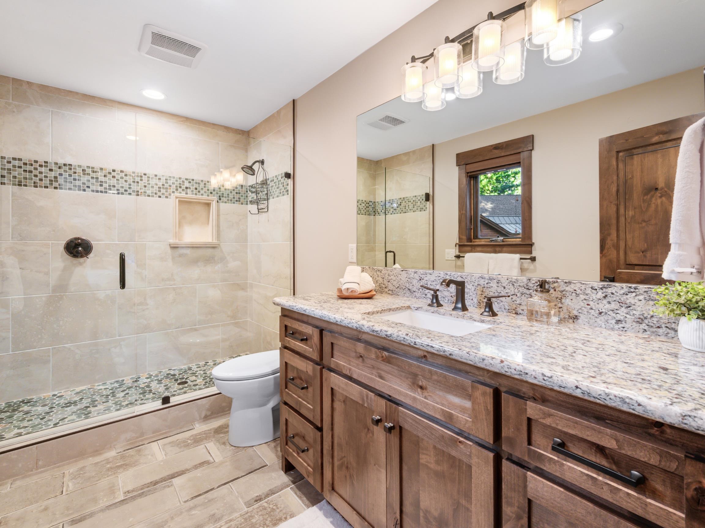 10613 Carson Range Road Truckee, CA 96161 - Photo 19 of 28 a bathroom with a granite countertop sink a toilet a mirror and shower