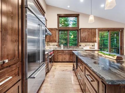 a kitchen with stainless steel appliances granite countertop a stove a sink dishwasher and a refrigerator with wooden floor