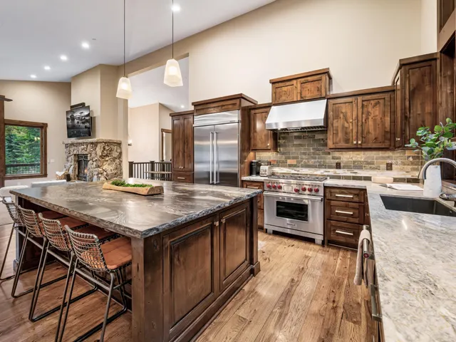 a kitchen with stainless steel appliances granite countertop a stove a sink dishwasher and a refrigerator with wooden floor