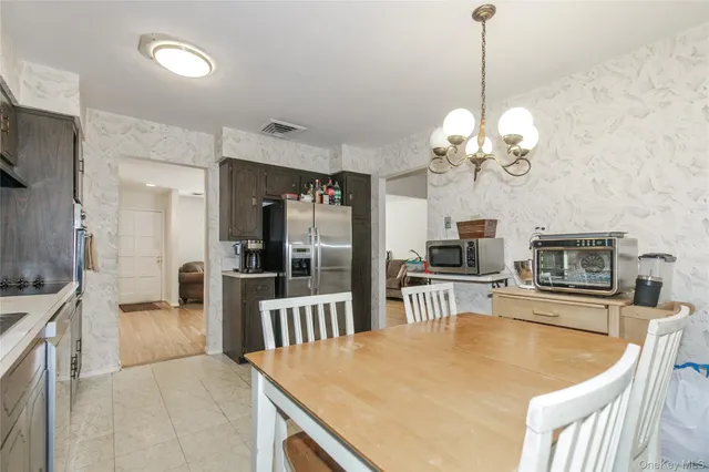 a dining room with furniture a chandelier and kitchen view