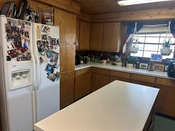 a kitchen with stainless steel appliances kitchen island granite countertop a refrigerator a sink a stove a microwave and wooden cabinets