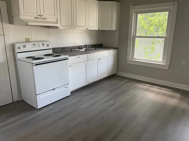 a kitchen with granite countertop wooden cabinets appliances and a window