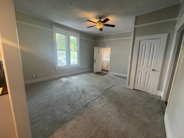 an empty room with ceiling fan and window
