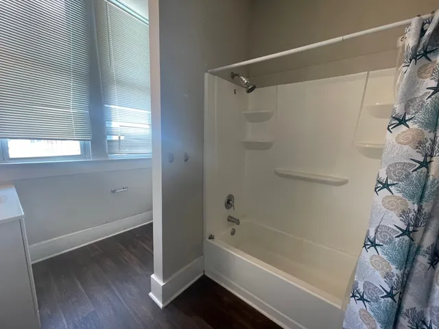 a bathroom with a bathtub a window and a shower
