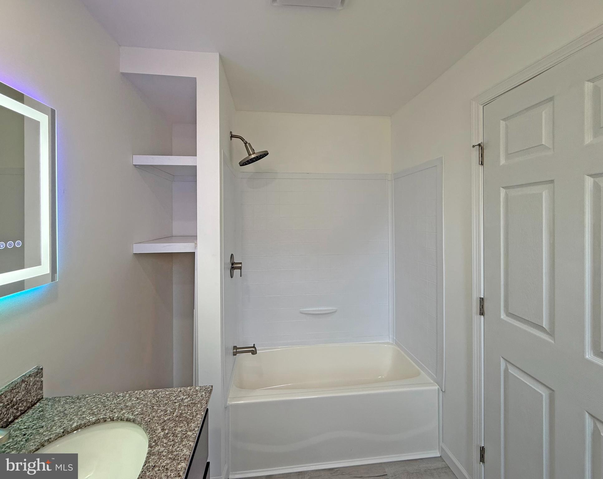 33308 Lighthouse Court, Unit D18 Lewes, DE 19958 - Photo 19 of 39 a bathroom with a granite countertop toilet a sink and bathtub