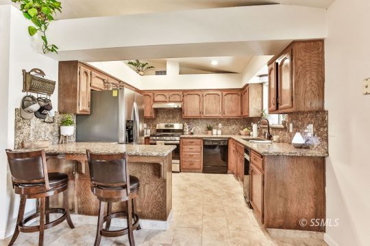 205 North Broadway Street Ridgecrest, CA 93555 - Photo 3 of 29 a kitchen with kitchen island granite countertop wooden cabinets and center island