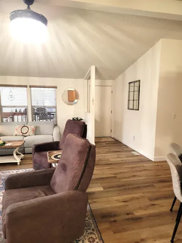 a living room with couches a coffee table and a flat screen tv with wooden floor