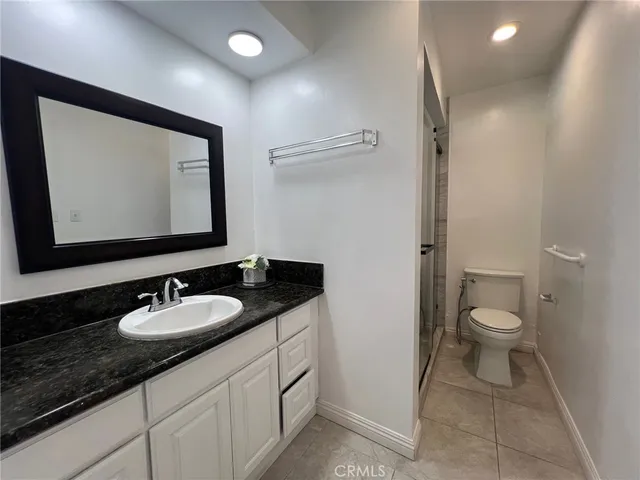 a bathroom with a granite countertop sink toilet and a mirror