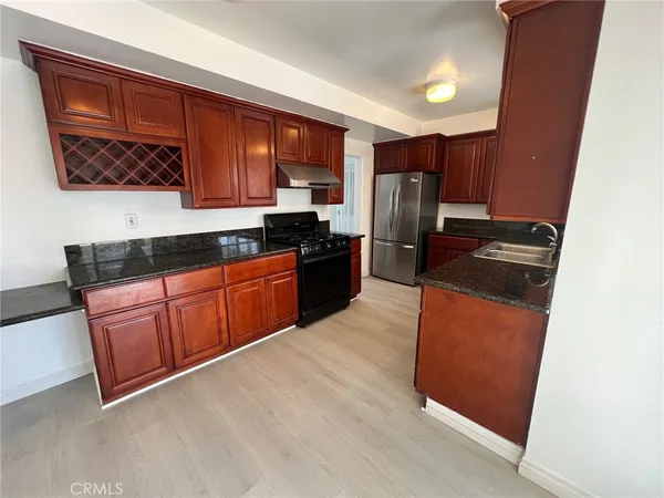a kitchen with granite countertop wooden cabinets a stove top oven and stainless steel appliances