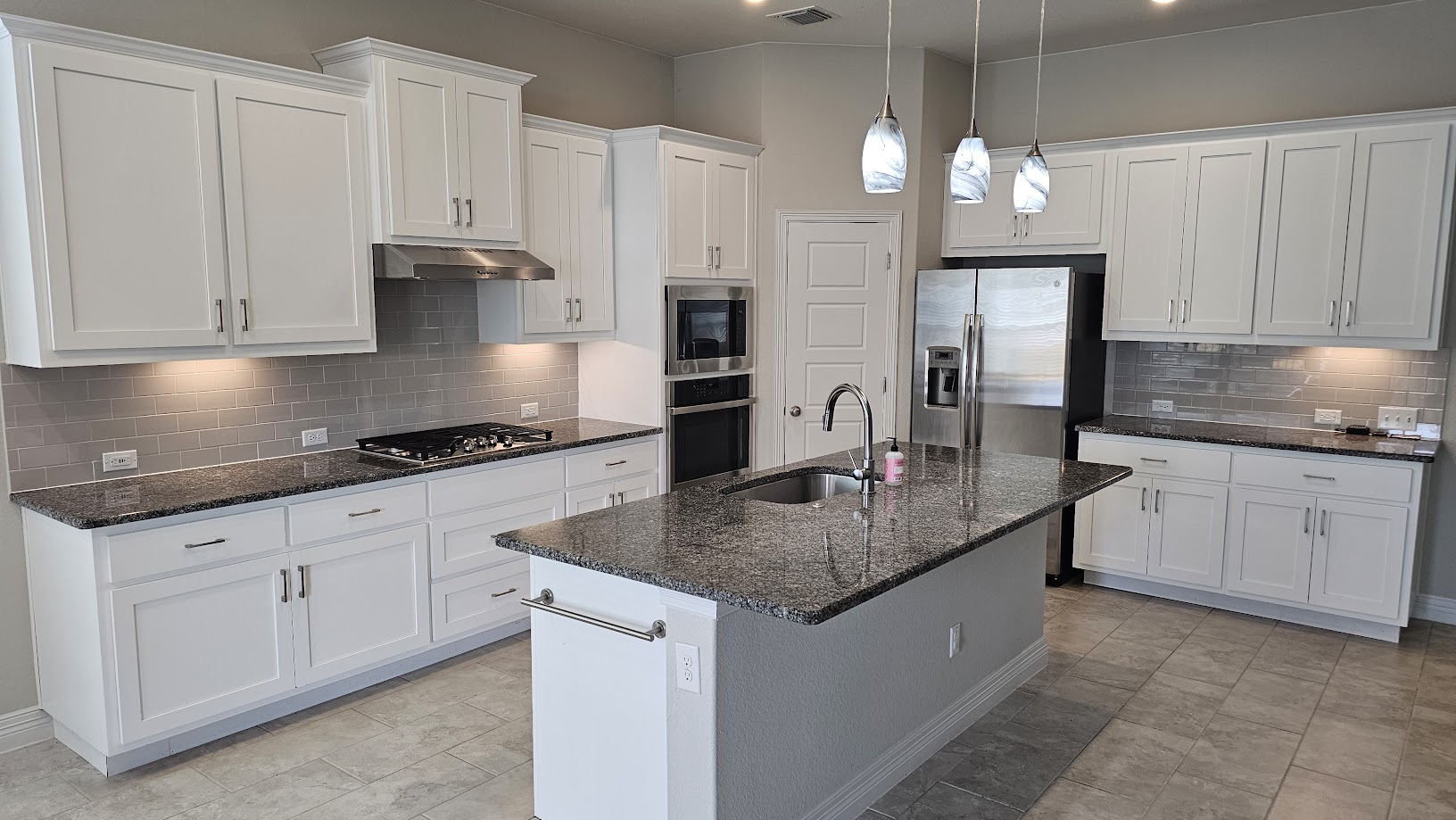 712 Muster Bend Georgetown, TX 78626 - Photo 18 of 26 Kitchen featuring a center island with sink, white cabinets, appliances with stainless steel finishes, under cabinet range hood, and a sink