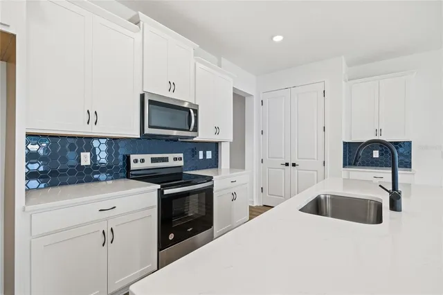 a kitchen with stainless steel appliances granite countertop a stove top oven a sink and dishwasher with white cabinets
