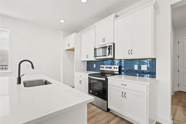 a view of kitchen with stainless steel appliances granite countertop white cabinets and refrigerator